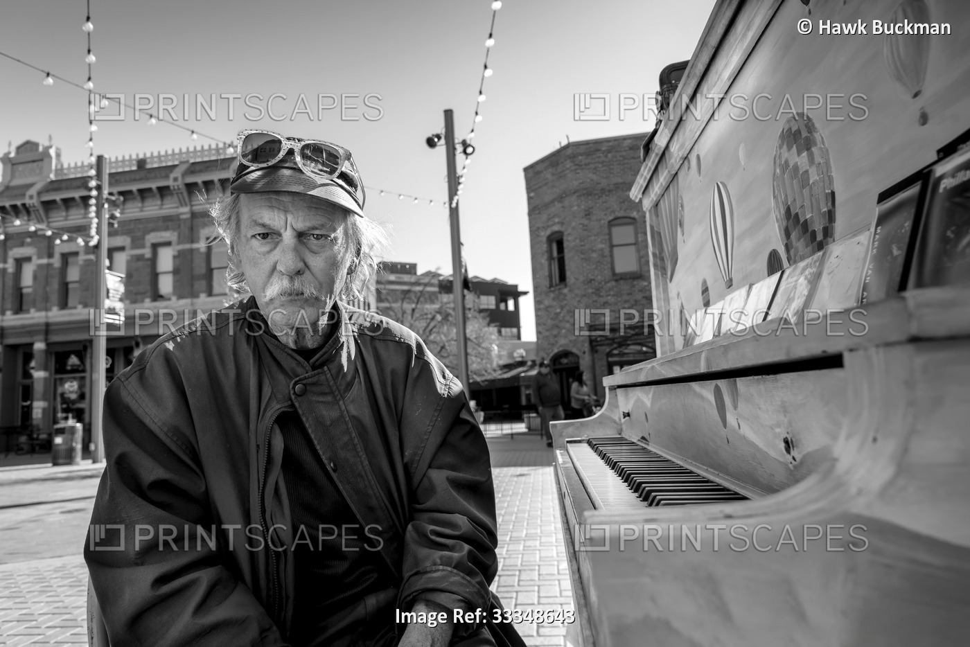 Black and white image of a homeless man sitting at a piano and looking at the ...